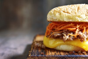 Homemade cheeseburger with fried minced meat and spicy carrot salad on a cutting board on rustic wooden background.Copy space.